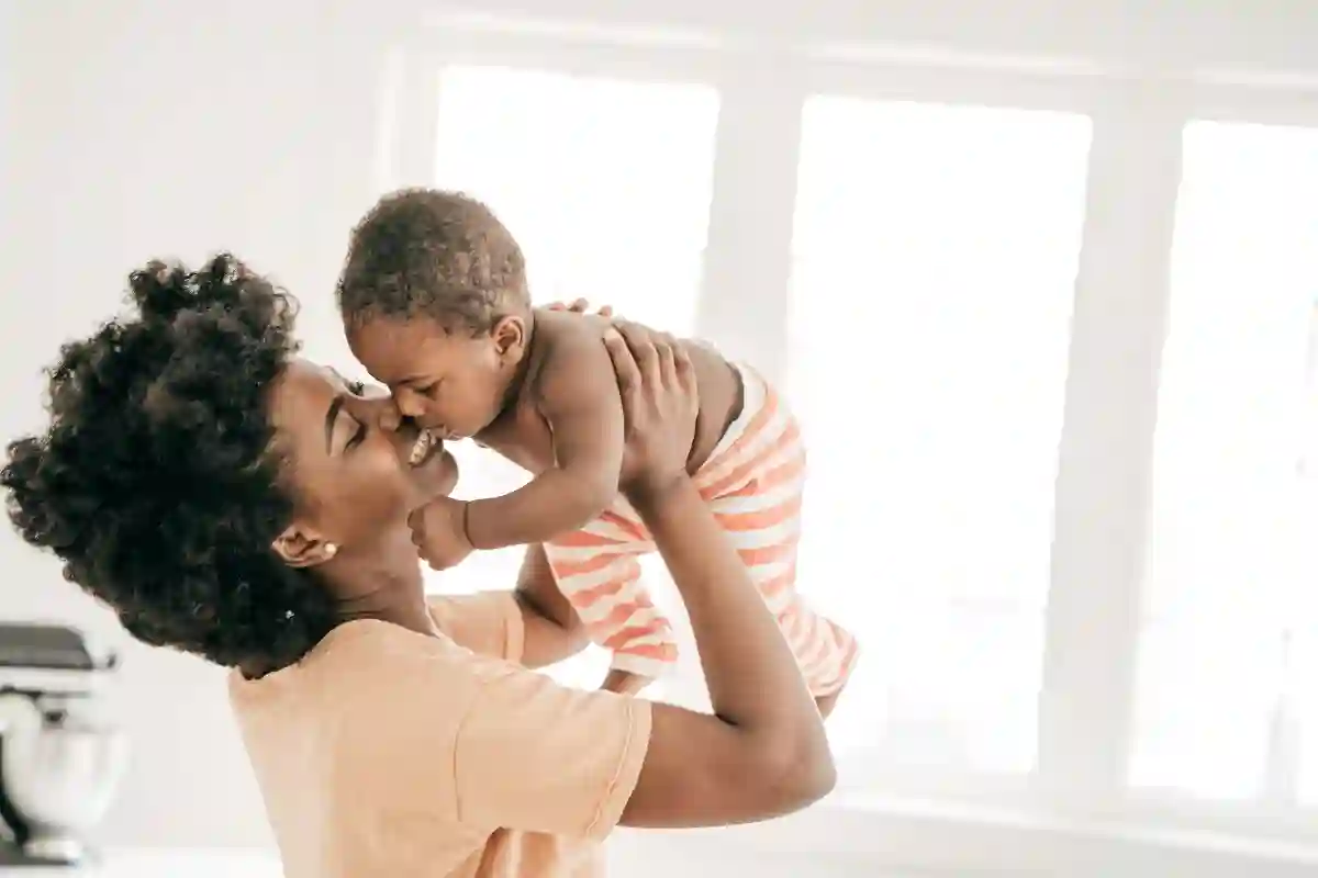 Smiling mom raising her baby in the air and snuggling his face