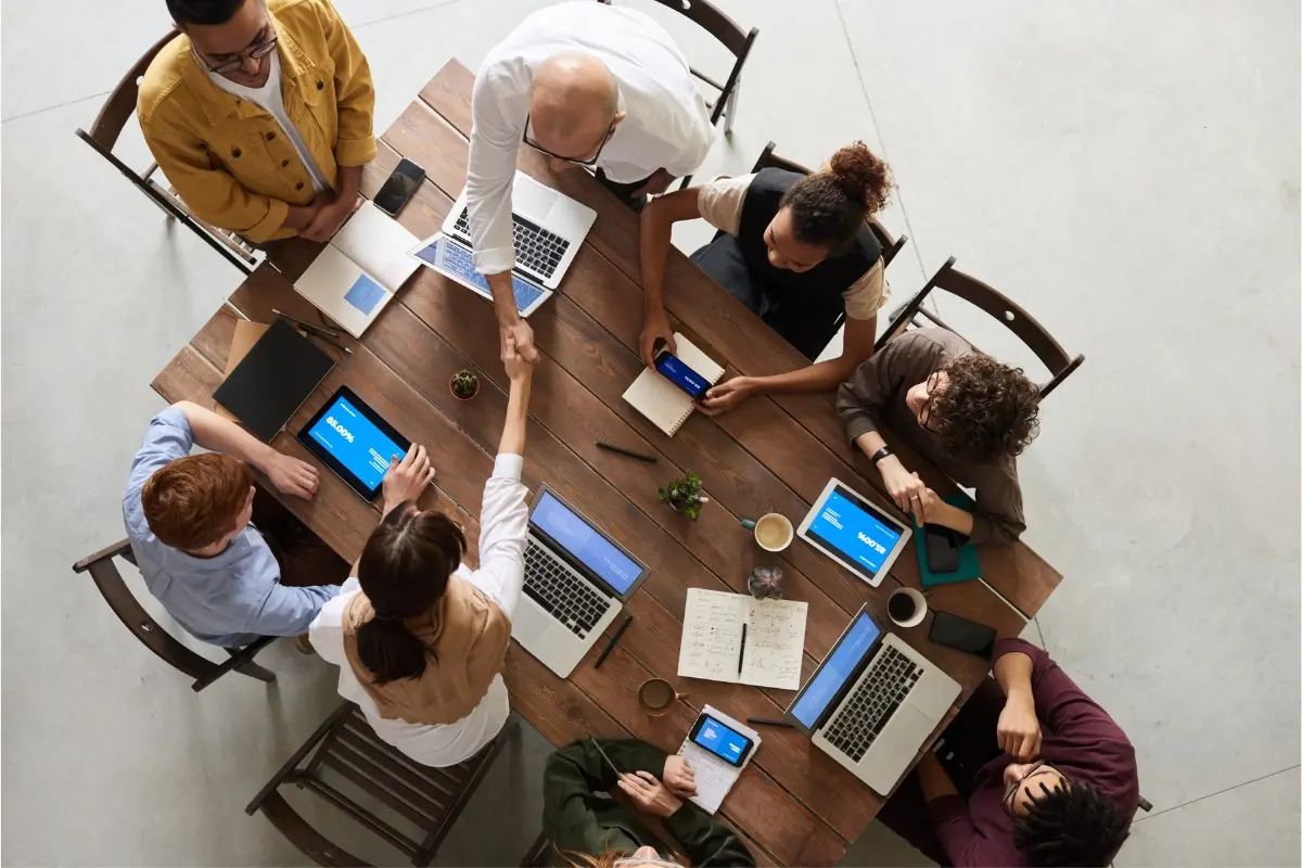 A group of people meeting and shaking hands across a table